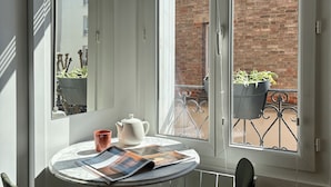 A corner of a room with a table, chairs, a window, and a view of a brick building and a bicycle. - Home Chic Home – Le Cocon de Paris La Défense (La Garenne-Colombes)