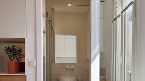 A modern bathroom with a white sink, a mirror, and a wooden floor. - Home Chic Home – Le Cocon de Paris La Défense (La Garenne-Colombes)