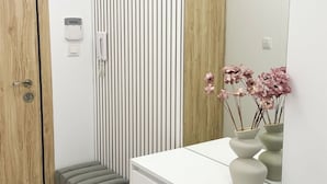 A modern bathroom with a wooden door, a white vanity with a mirror, and a vertical striped wall. - 2BR Apartment | Free Parking | Central (Plovdiv)