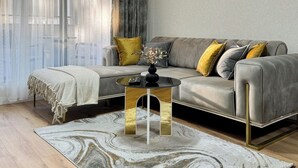 A modern living room with a grey sofa, a small round table, and a patterned rug. - 2BR Apartment | Free Parking | Central (Plovdiv)