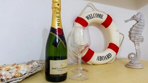 A bottle of Moët & Chandon champagne, a glass, a life preserver with "WELCOME ABOARD" text, and a seahorse decoration on a wooden surface. - Appartamento Golden Beach Porto Cesareo (Porto Cesareo)