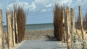 Un camino de grava que conduce a una playa, con postes de madera a cada lado.