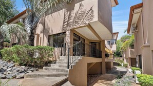 A modern building with a central staircase, surrounded by greenery and palm trees. - Dual Kitchens, Pool, 3-min walk to the Beach (Playa Ocotal)