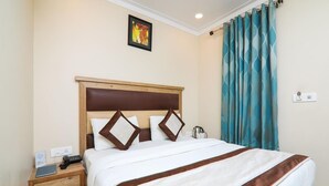 Quarto de hotel com uma cama, mesa de cabeceira, telefone e um quadro na parede.