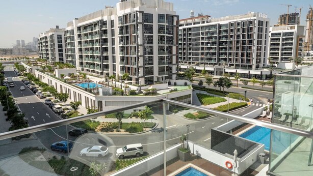 A modern residential building with multiple floors, a central courtyard with a swimming pool, and a glass bridge connecting different sections. - Unique Studio in Azizi Riviera (Dubai)