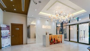 A modern hotel lobby with a reception desk, a chandelier, and a glass storefront. - Unique Studio in Azizi Riviera (Dubai)