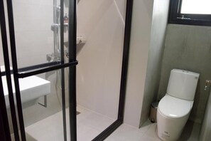 Un baño con cabina de ducha de vidrio, lavamanos blanco y retrete.