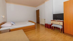 A small, well-lit room with a single bed, a desk with a computer, and a wardrobe. - Apartman Franjo 2 (Dramalj)