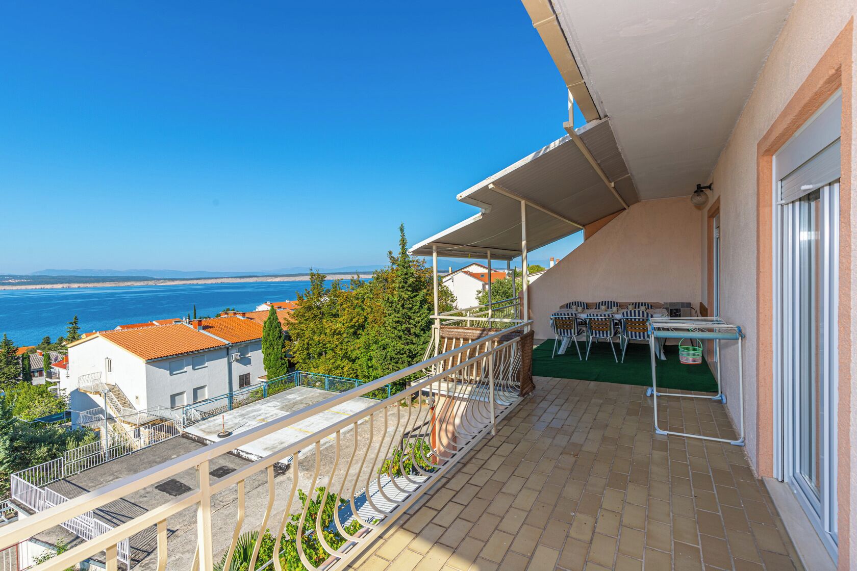 Un balcon avec vue sur la mer, des meubles d’extérieur et un espace abrité.