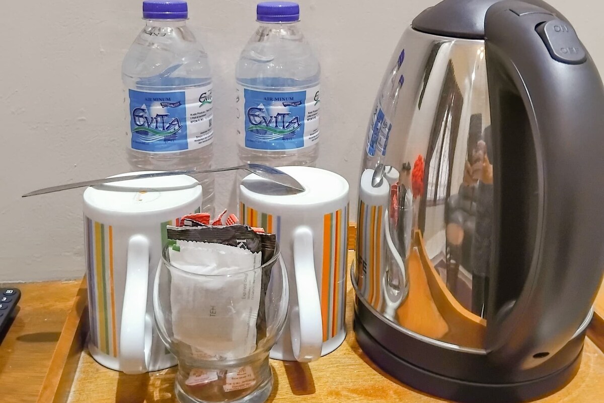 Eine Küchenzeile mit Wasserkocher, zwei Wasserflaschen, einer Tasse und einem Glas.