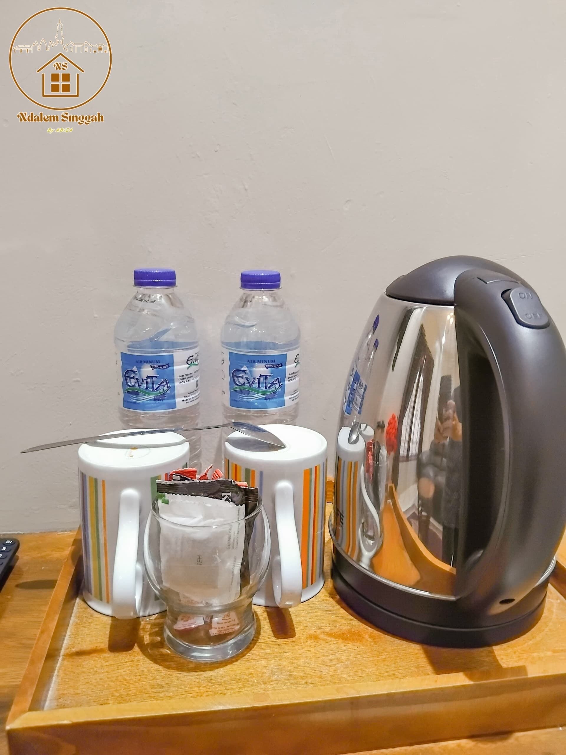 A kitchen area with a kettle, two water bottles, a mug, and a glass.