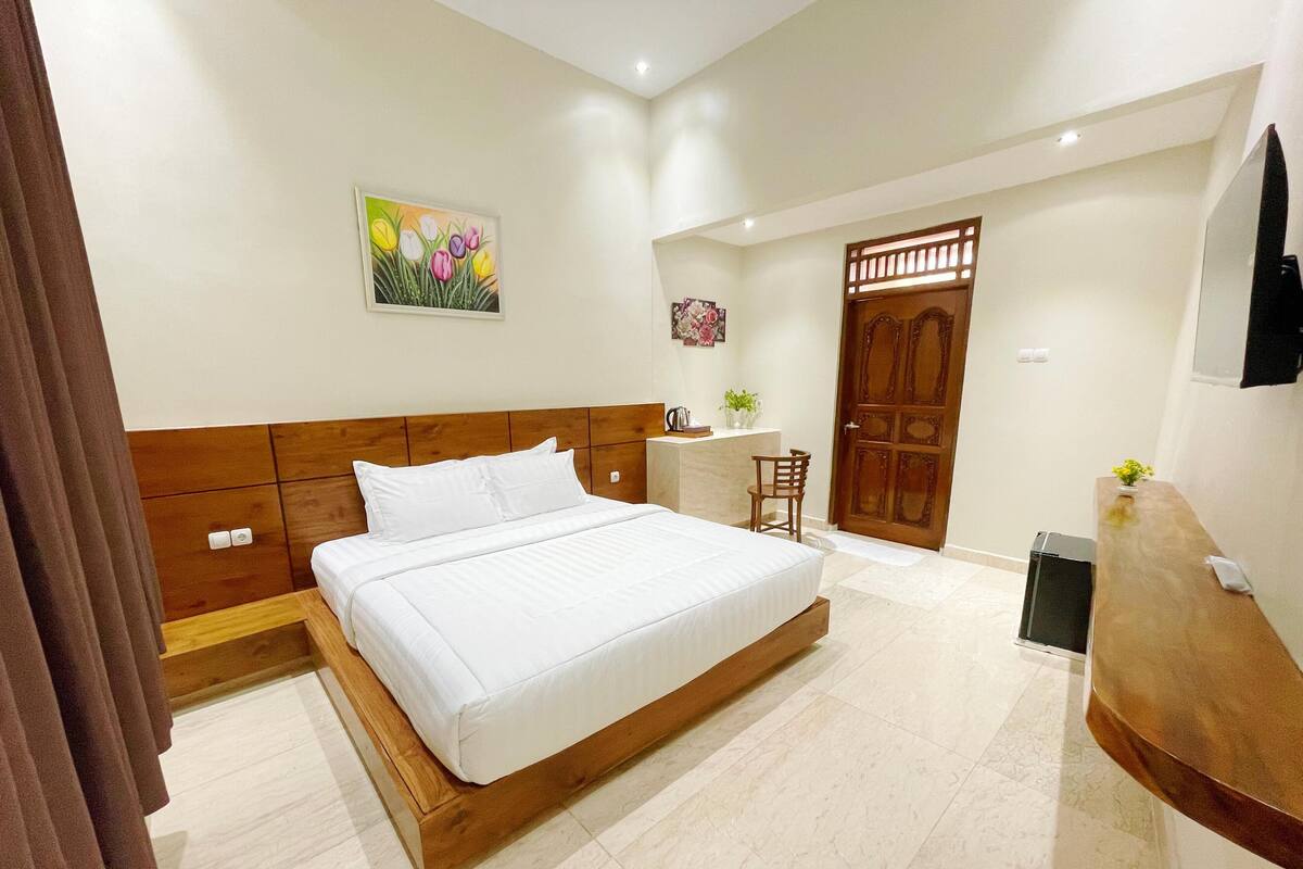 Une chambre à coucher avec un lit en bois, un bureau, une chaise et une porte.