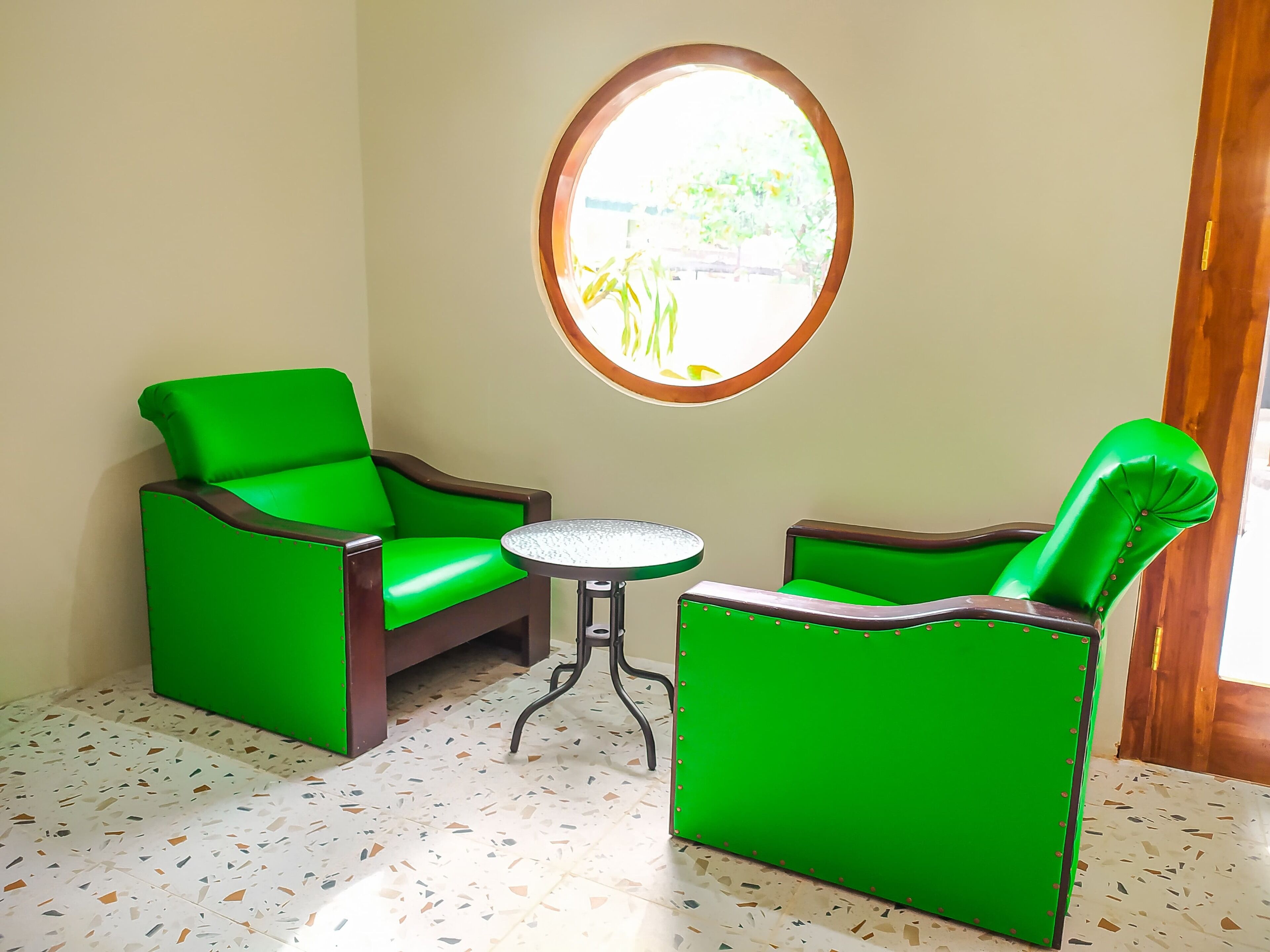 A room with two green armchairs and a small round table.