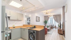 Een moderne keuken met een ingebouwde wasmachine, een eetgedeelte met uitzicht en een woonruimte met een kroonluchter.