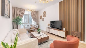 Een moderne woonkamer met een bank, fauteuil, salontafel, televisie en een eethoek met een tafel en stoelen.