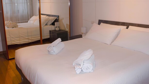 A neatly made bed with towels, a bedside table with a lamp, and a mirror reflecting the room. - CASA IL FIORE (Florence)