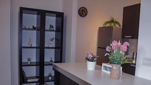 A kitchen with a white countertop, a black cabinet, and a potted plant with pink flowers. - CASA IL FIORE (Florence)