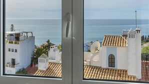 Blick auf die Küste vom Fenster aus, mit Blick auf ein Gebäude mit einem Ziegeldach und einer weißen Fassade.