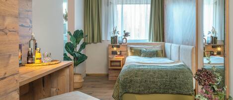 Un dormitorio con cama, mesitas de noche, un escritorio de madera y un espejo.