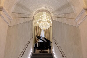 A grand piano on a staircase leading to a room with a chandelier. - A stay at a prestigious location in the heart of Florence (Firenze)