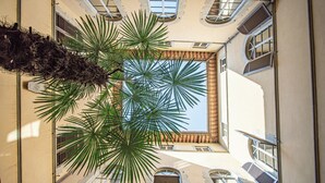 A high-ceiling atrium with a central skylight, large windows, and a palm tree. - Stay in a prestigious place of interest in Florence in the city center (Firenze)