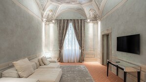 A spacious living room with a large sofa, a flat-screen TV, and a decorative ceiling. - Stay in a prestigious place of interest in Florence in the city center (Firenze)