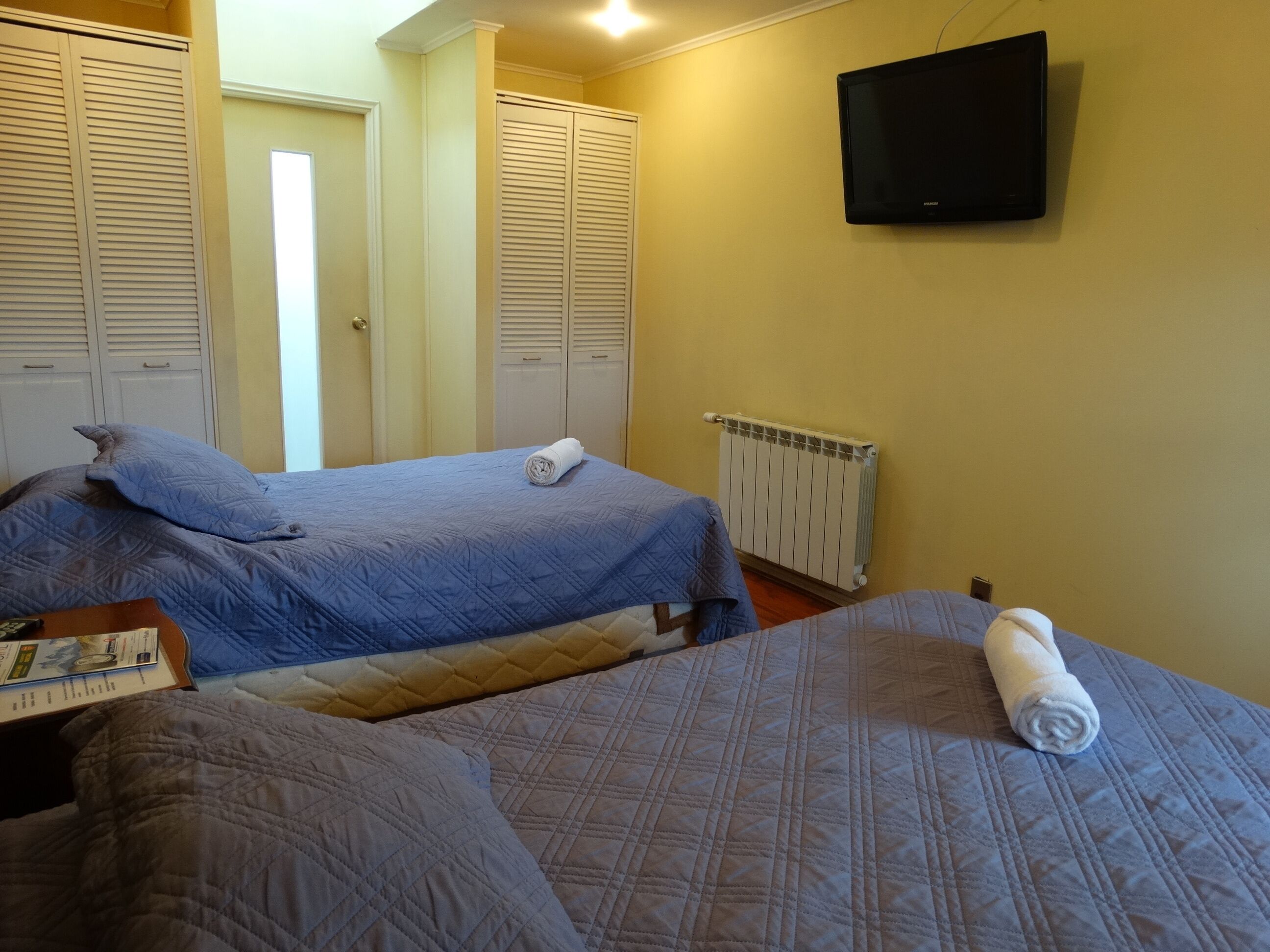 A hotel room with two beds, a TV, and a radiator.