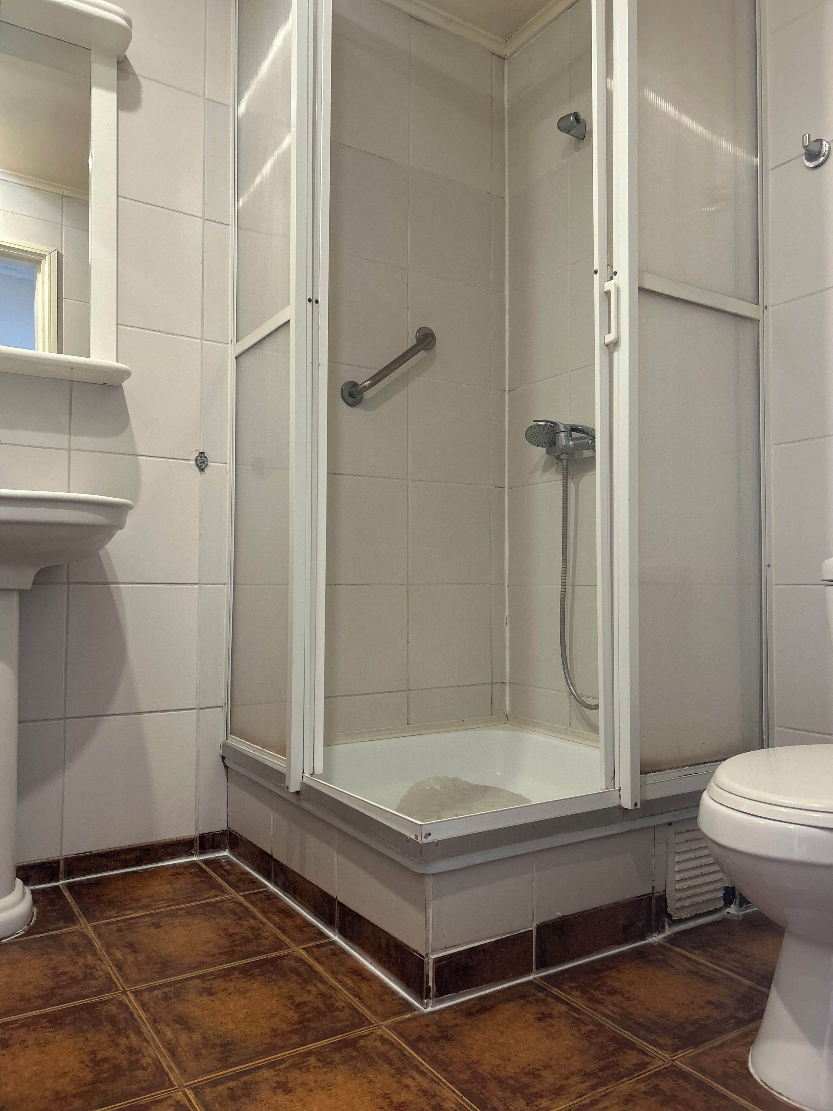 Un baño con cabina de ducha, inodoro y lavamanos.