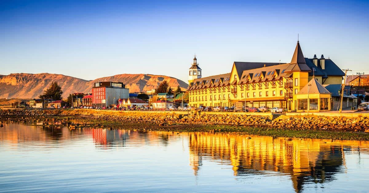 A historic building with a prominent tower, situated by a calm body of water with a clear reflection.