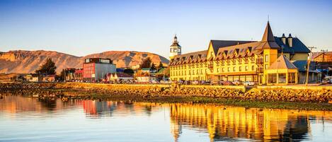 A historic building with a prominent tower, situated by a calm body of water with a clear reflection.