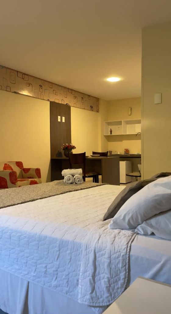 Habitación de hotel con cama, escritorio y kitchenette.
