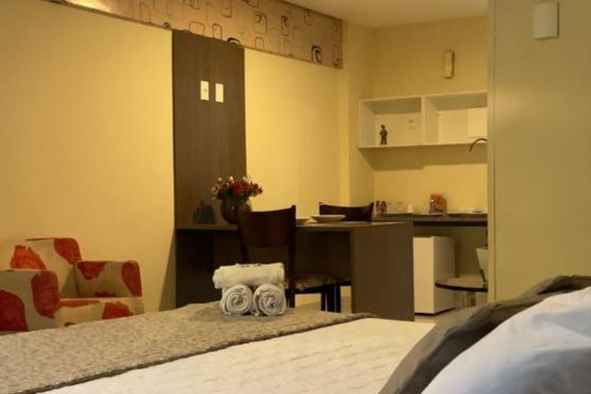 A hotel room with a bed, a desk, and a kitchenette.