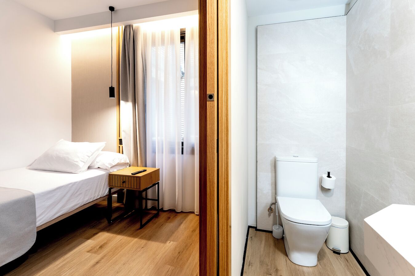 Hotelkamer met een bed, bureau, stoel, toilet en douche.