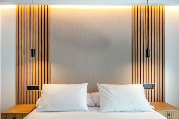 A modern bedroom with a wooden panel headboard, a bed with white linens, and two bedside tables.