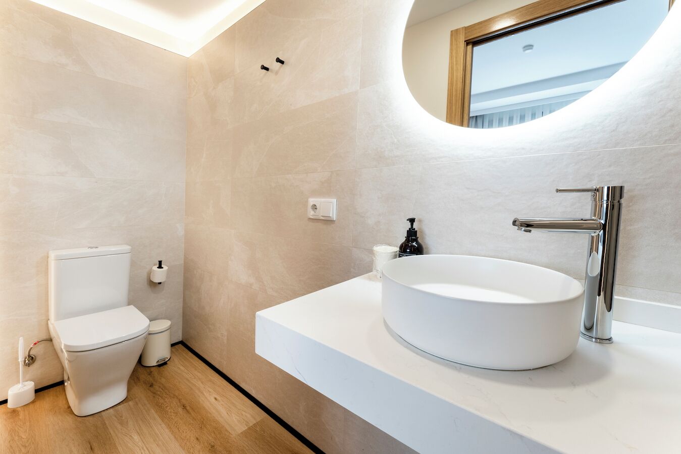 A modern bathroom with a toilet, sink, and mirror.