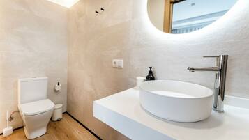 A modern bathroom with a toilet, sink, and mirror.