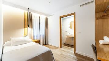 Habitación de hotel con cama, mesita de noche y armario de madera.