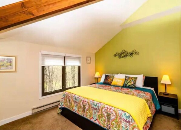 A bedroom with a bed, two bedside tables, a window, and a wall decoration.