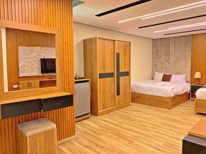 Een moderne slaapkamer met een houten garderobe, een bed, een klein bureau en een spiegel.