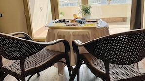 A balcony with a table set for breakfast, wicker chairs, and a view of pyramids. - Roone Pyramids View Inn (Giza)