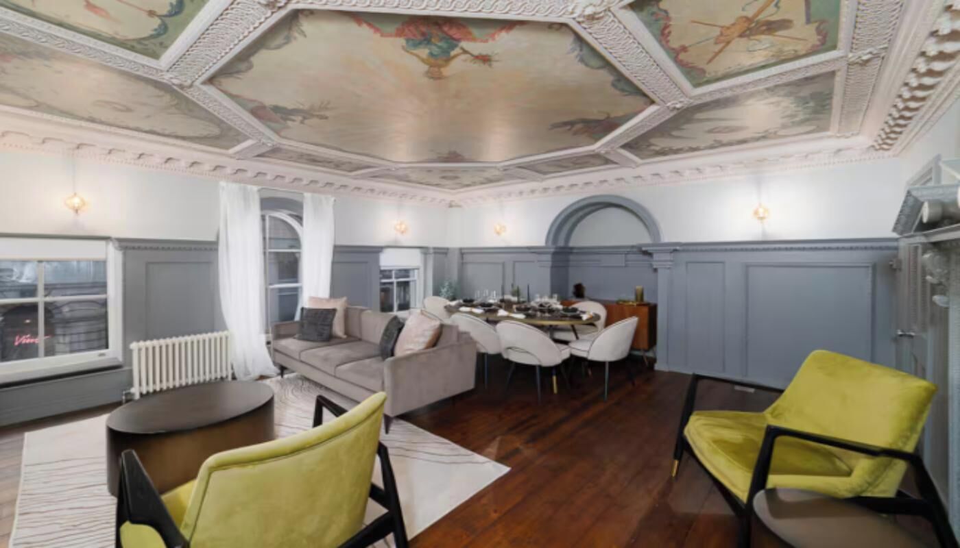 Une pièce spacieuse avec un plafond haut, un coin repas et un espace détente avec des canapés et des fauteuils.