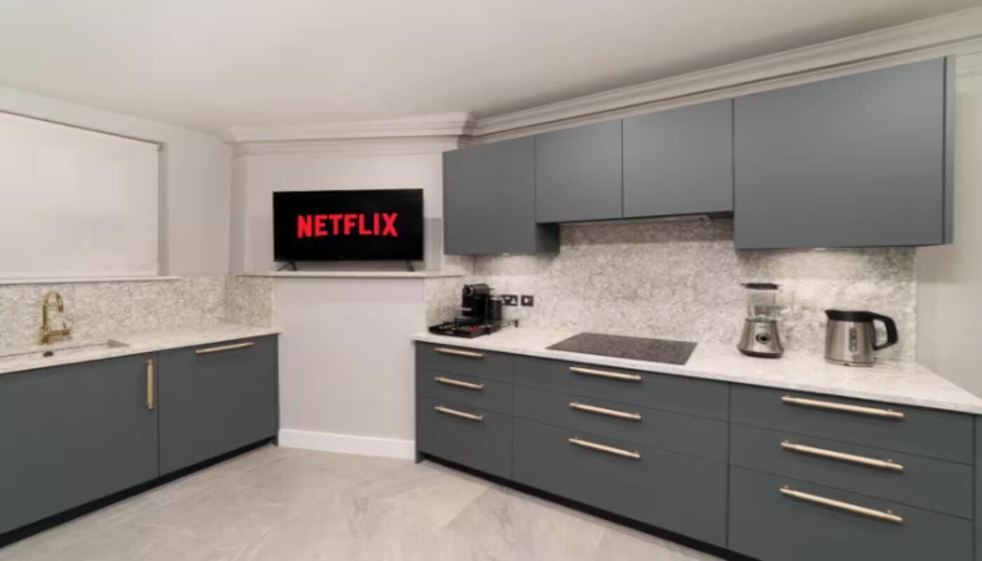 A modern kitchen with grey cabinets, a built-in microwave, and a coffee maker.