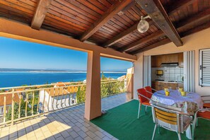 Un balcon avec vue sur la mer, une table avec des chaises et un coin cuisine.