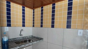 Una cocina pequeña con un lavamanos, un grifo y salpicadero de azulejos.