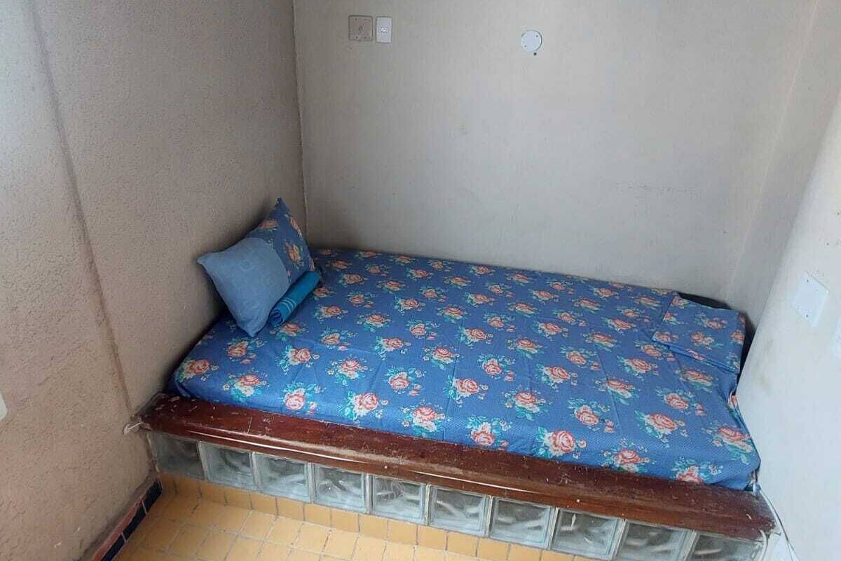 A small, enclosed room with a single bed, a wooden ceiling, and a tiled floor.