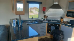 A compact kitchen with a central island, a stove, and a sink. - Bay View - fantastic views of Whitsand Bay and the Rame Peninsula (Rame)