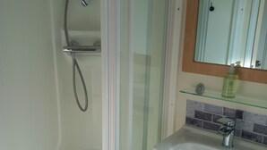 A bathroom with a glass-enclosed shower, a sink with a mirror above it, and a tiled backsplash. - Bay View - fantastic views of Whitsand Bay and the Rame Peninsula (Rame)