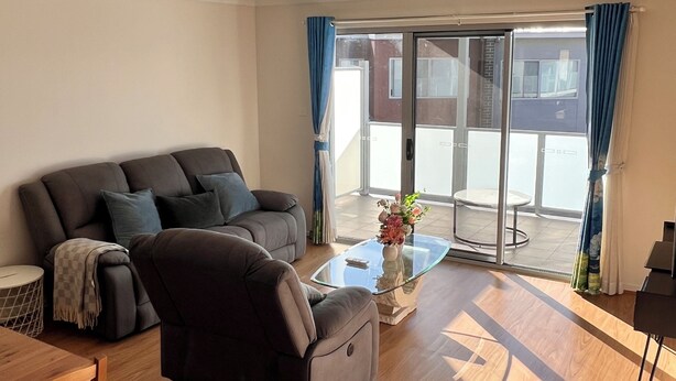 Un salon moderne comprenant un canapé, un fauteuil, une table basse en verre et une table à manger.
