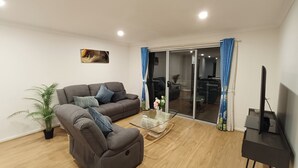 Un salon comprenant un canapé, un fauteuil inclinable, une table basse et un meuble pour la télévision.