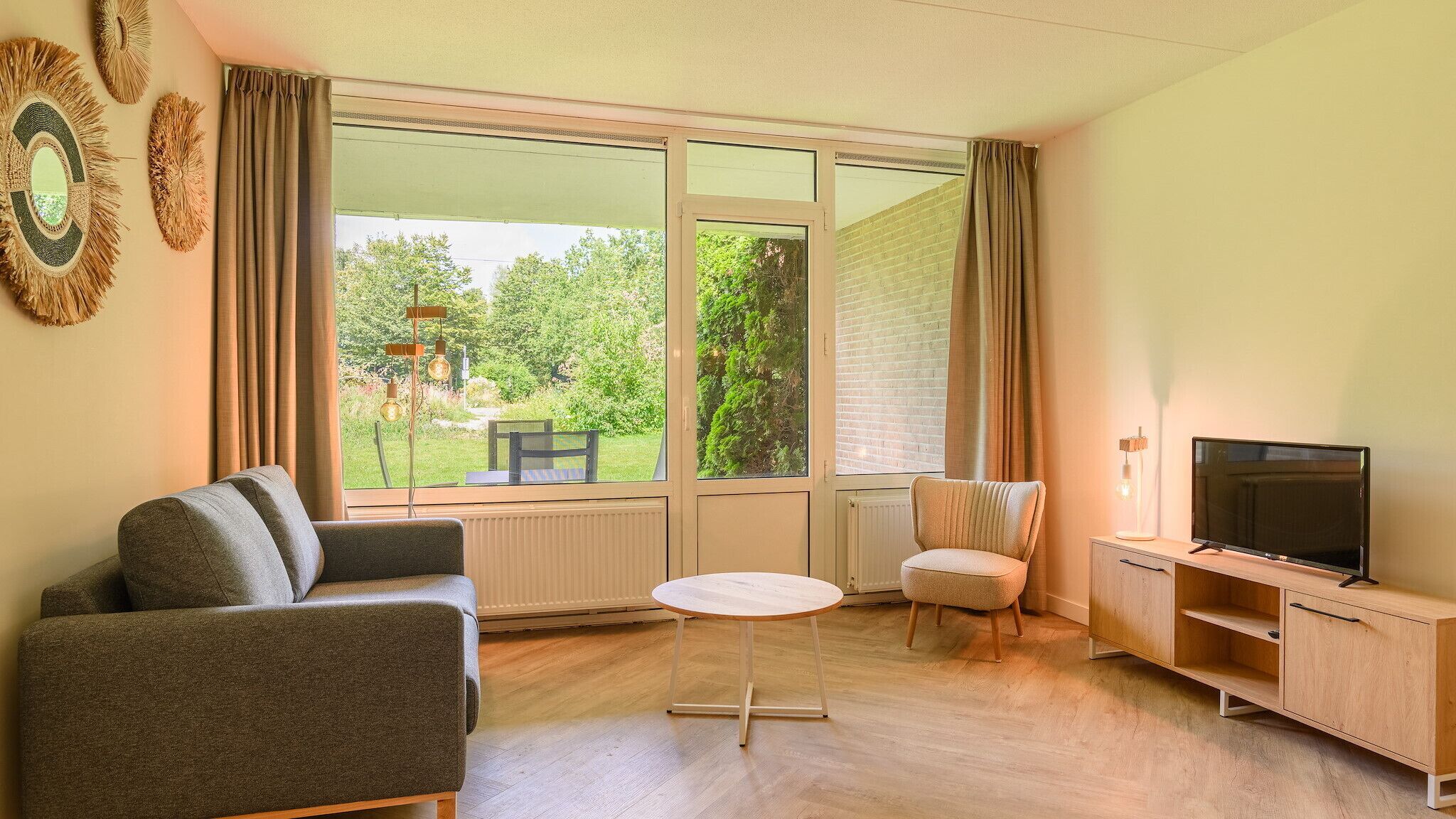 A living room with a sofa, a small round table, a TV, and a chair.